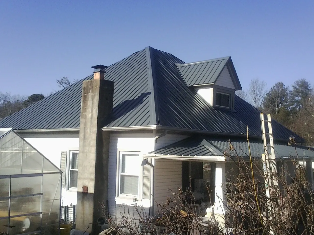 Dark blue standing seam metal roof on a white farmhouse with dormer — Slate & Tile Roof Repair by Roofing Brothers in Perrysburg