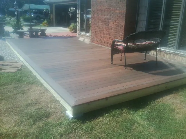 New wood deck and wicker chair beside a brick house in Perrysburg