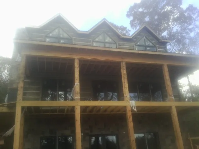 Dormers and porch framing on a large log home under construction — Roof Coating work by our crew in Perrysburg