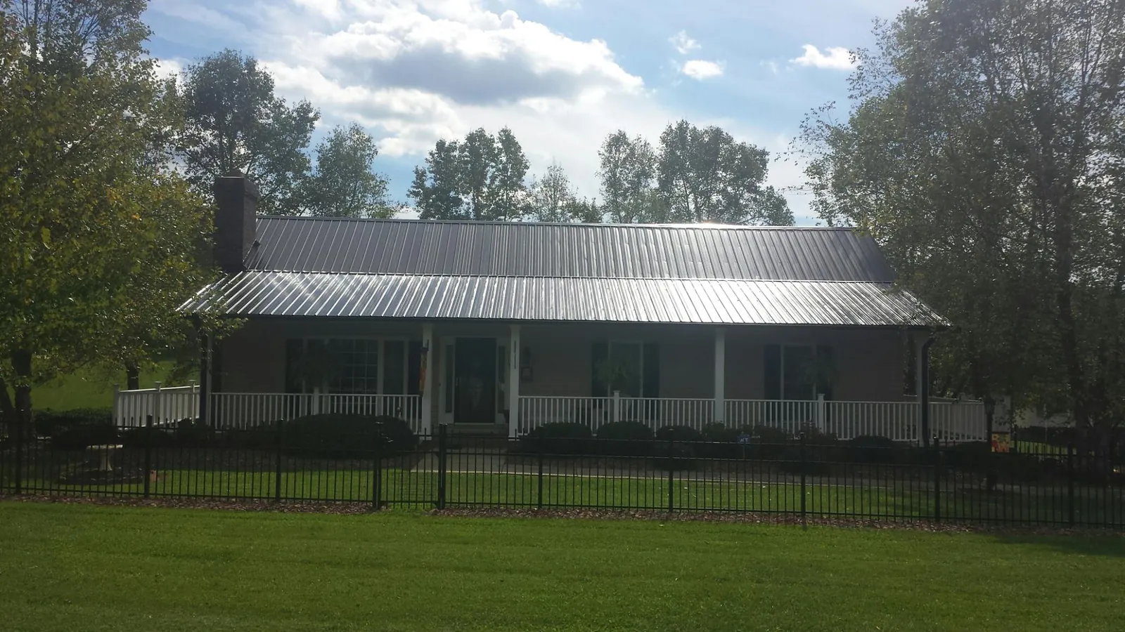 Gray metal roof on a brick ranch with a full width front porch — Gutter Guard Installation work by our crew in Perrysburg