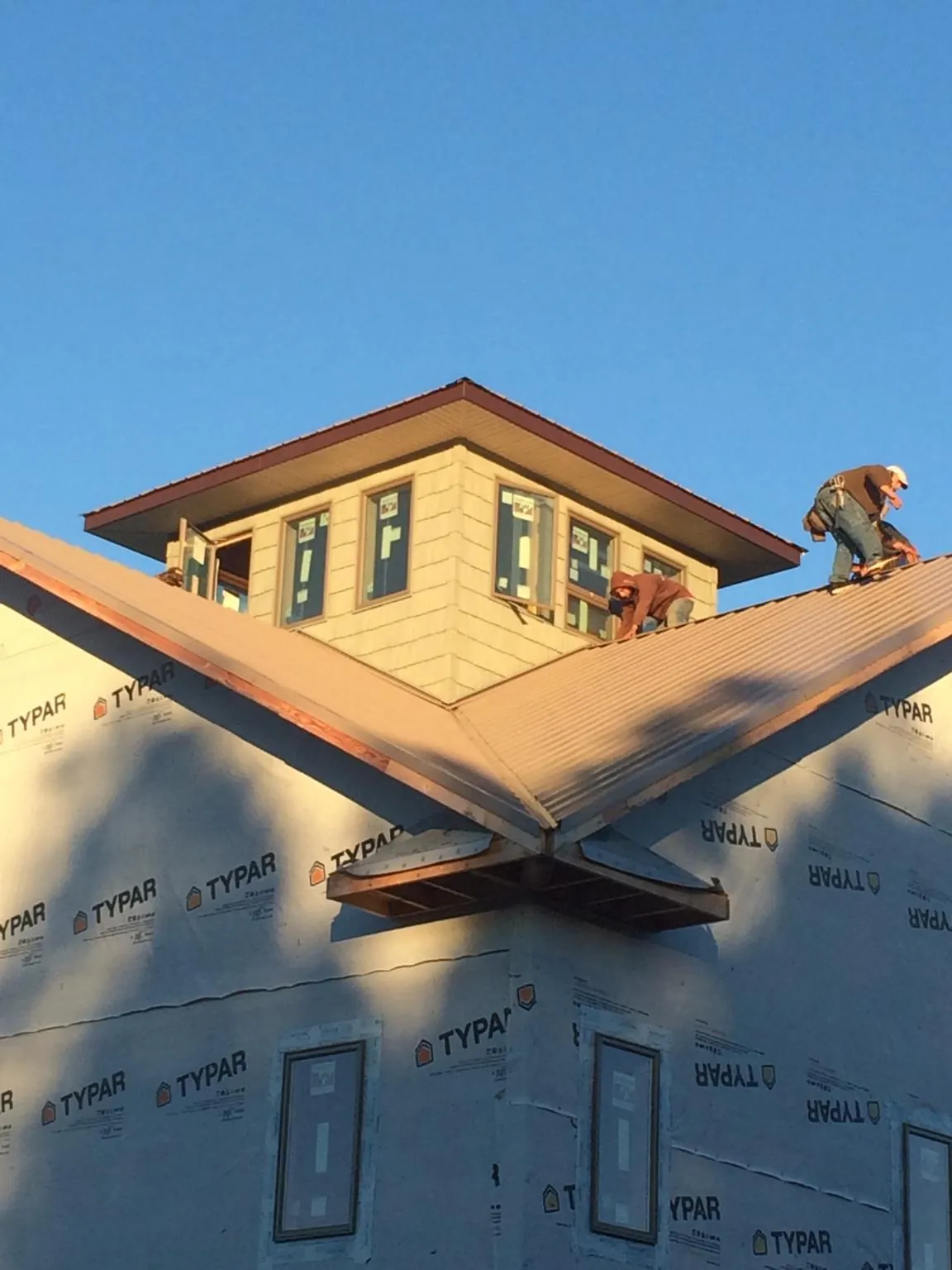 Roofers working around a rooftop cupola on a new metal roof at sunset — Roof Waterproofing in Perrysburg by Roofing Brothers